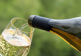 pouring a glass of white wine with a green background