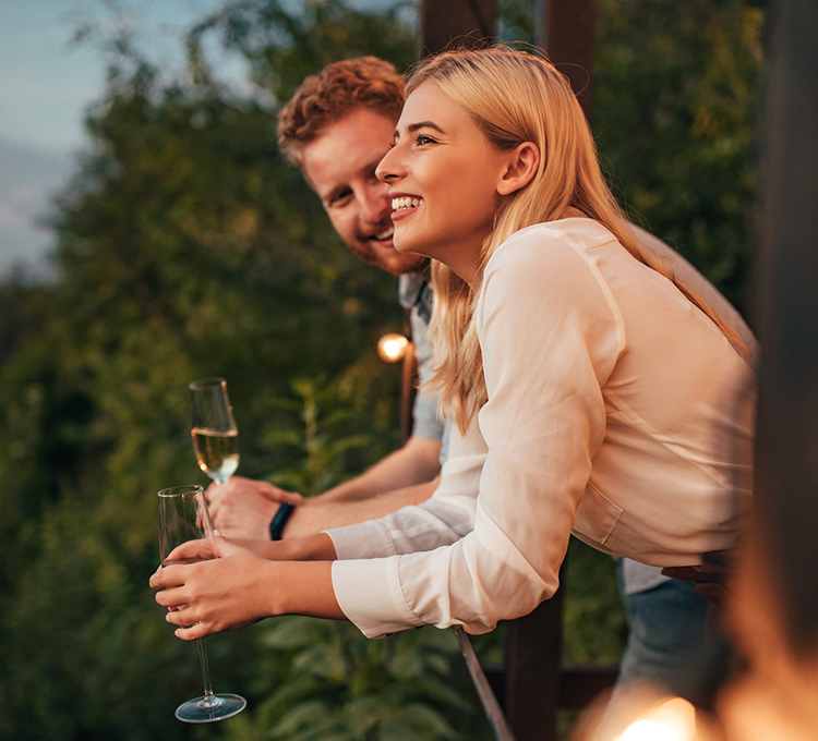 Young guy and lady smiling holding a glass of champagne