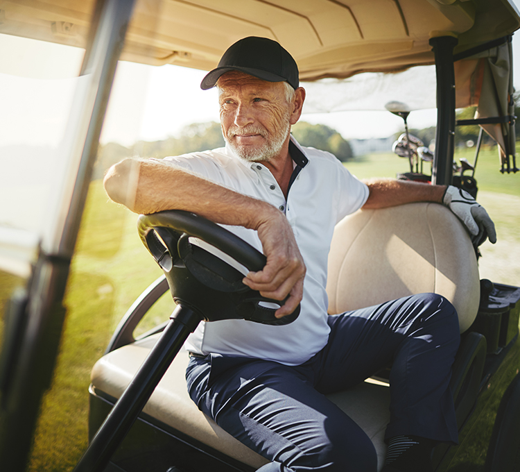 Elderly man sitting in a golf cart looking forward