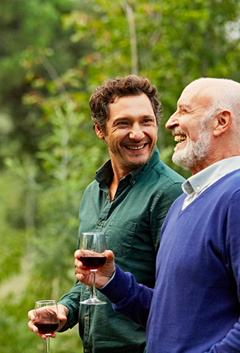 Guy and his father smiling and holding a glass of red wine