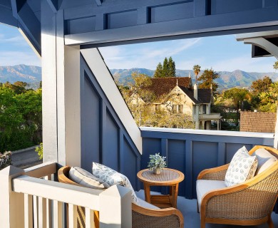 A blue balcony of a house and the mountains in the distance.