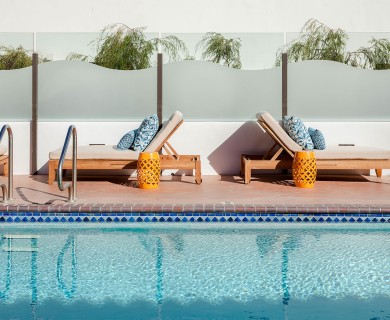 Closeup view of a pool with pool lounge chairs and the sun shining.
