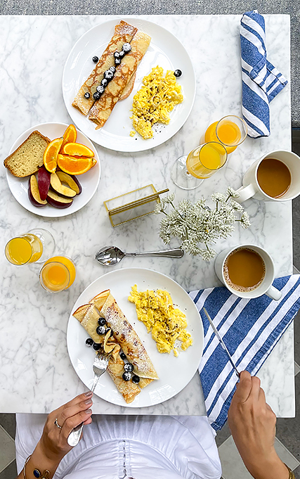Aerial shot of marble dining table with coffee, orange juice, and breakfast.