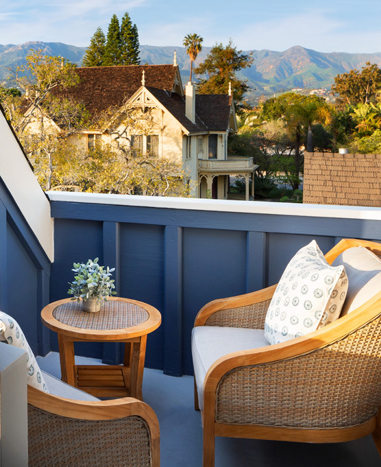 A close up of wicker chairs and table on a blue balcony.