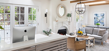 A reception area with white walls and gray furniture with natural light coming in.