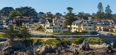 Zoomed out shot of yellow homes located next to a rocky coastline during the day.