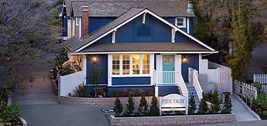 Dark blue and white house with lights on inside.