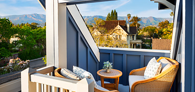 Sun shining over two chairs on a blue and white balcony.