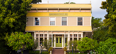A bright yellow building with lots of trees around it at sunset.