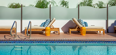 Lounge chairs and small orange tables located next to the pool.