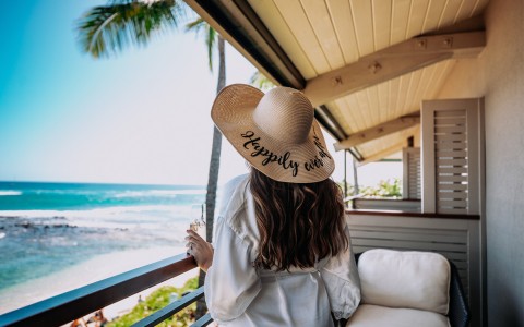 woman wearing a hat that says happily ever after while looking at the ocean
