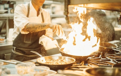 a chef cooking a dish with a large flame