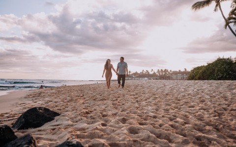 a couple holding hands while walking on the beach