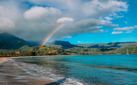 view of the ocean and the mountains with a rainbow shining above