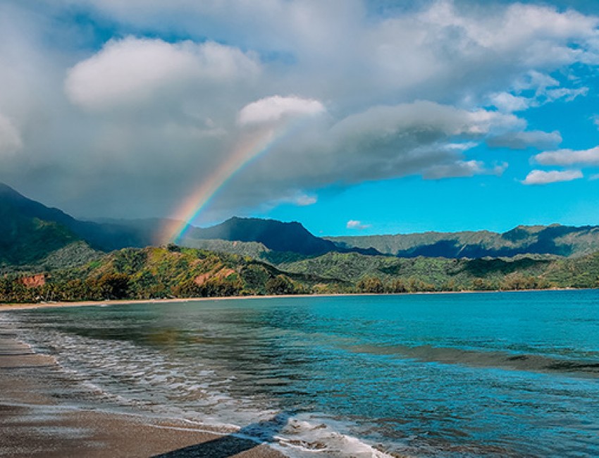 view of the ocean and the mountains with a rainbow shining above
