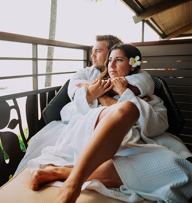 man hugging a woman while lounging on a balcony chair