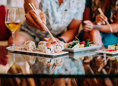 man picking up a piece of sushi from his plate with chopsticks