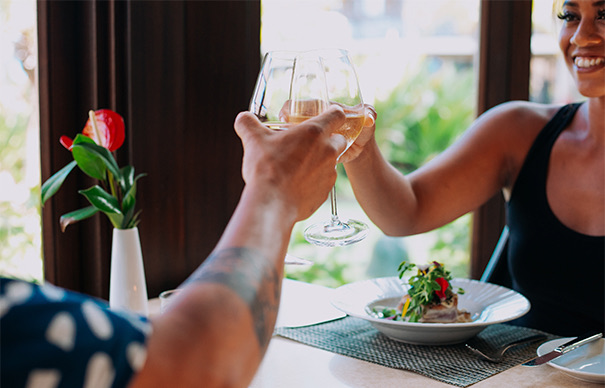 a couple clinking their glasses of wine while enjoying an elegant meal