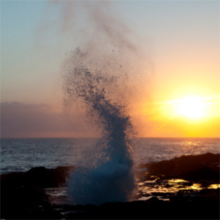 Wave crashing on to rocks at sunset