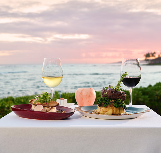 view of two elegant dishes served with wine along the beach