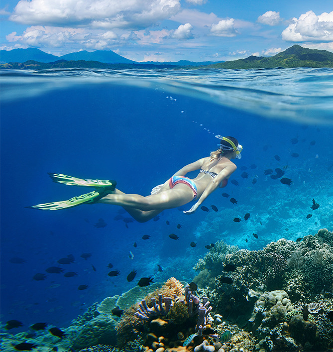 woman scuba diving in the ocean above coral reefs
