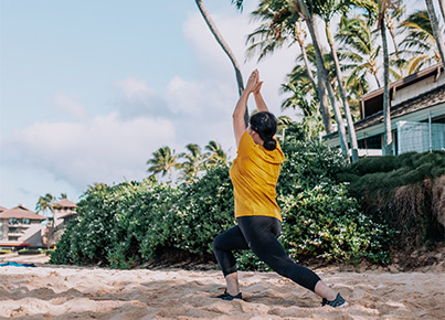 woman doing yoga in the sand next to the resort