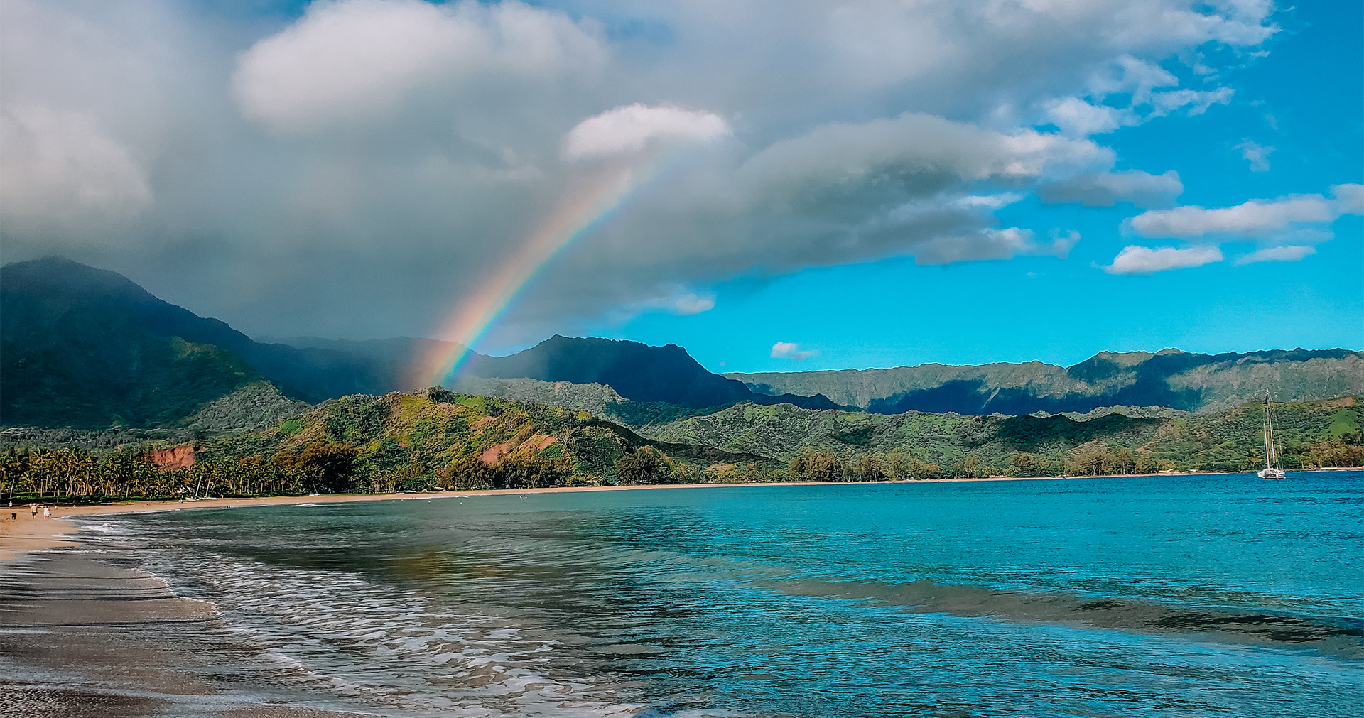 a rainbow shining over the ocean and the mountains
