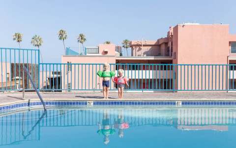 2 kids wearing floaties on pool deck
