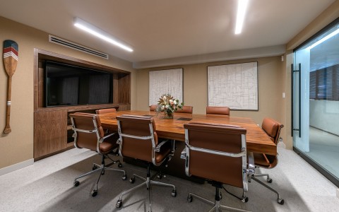 meeting room with brown table and chairs and large tv screen
