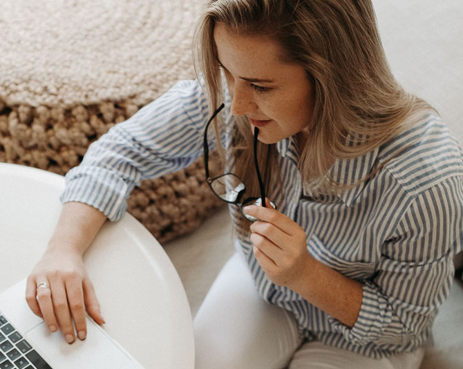 woman on laptop while golding glasses to her mouth