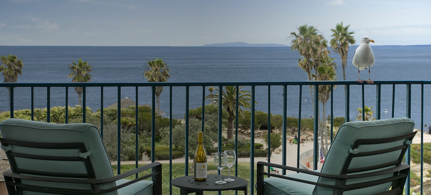 patio view of ocean with two chairs and table with wine