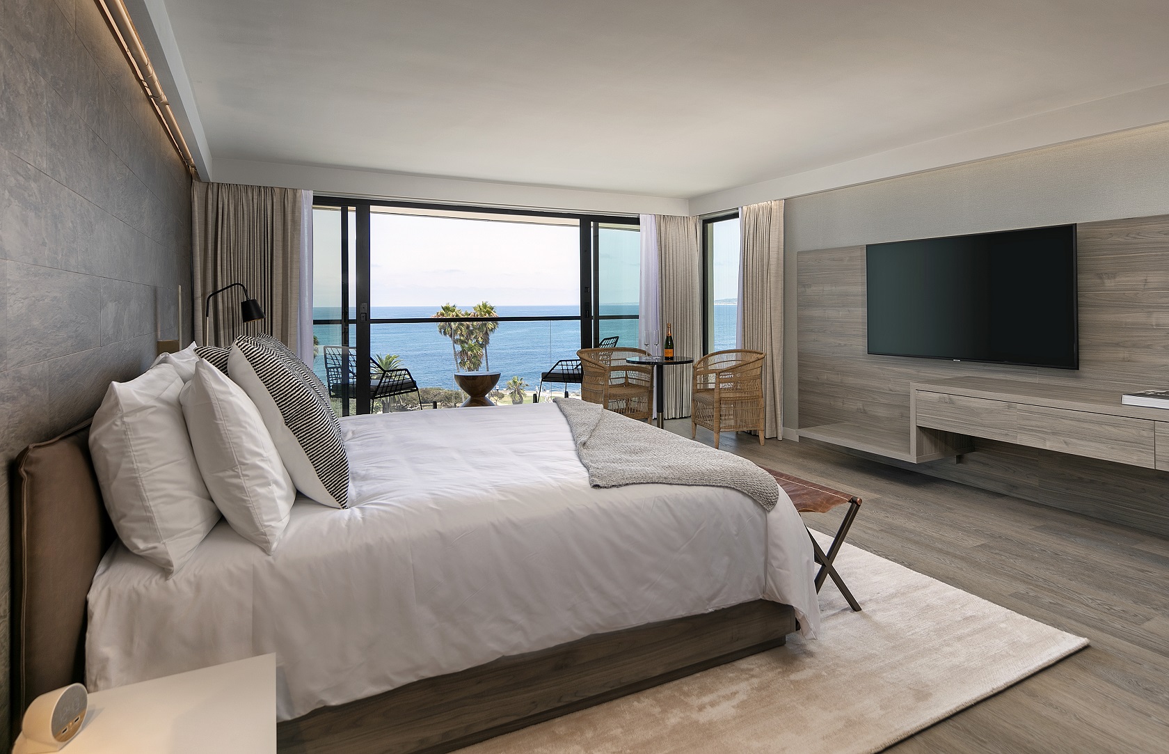 hotel room with large bed and a wall to wall window with a view of the water