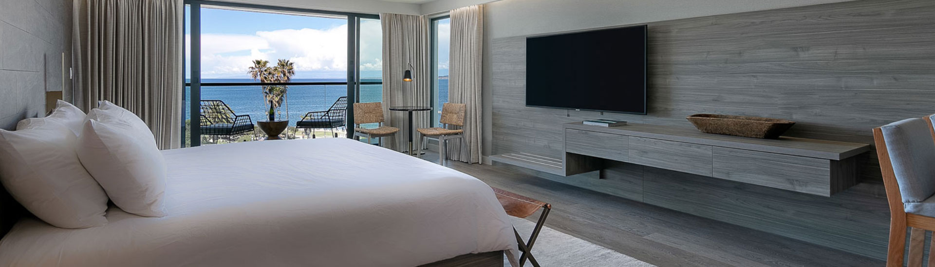 room with large white bed and ocean view