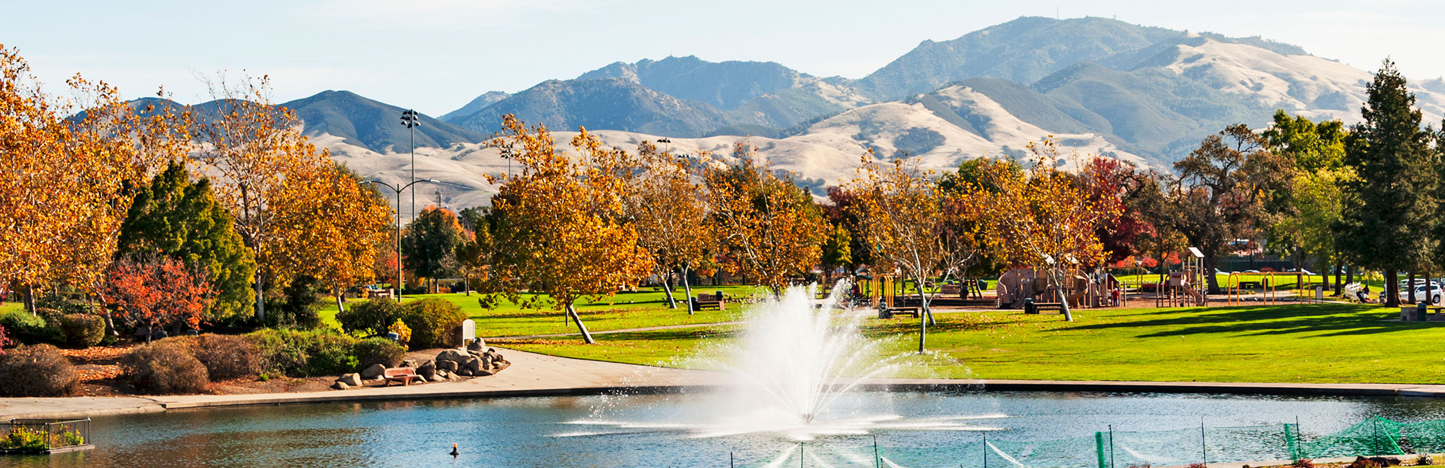 Lake with water fountains & autumn trees in the back