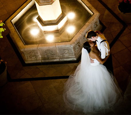 bride and groom kissing by a fountain