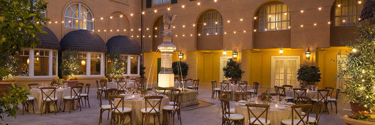 courtyard with tables and chairs sitting below string lights