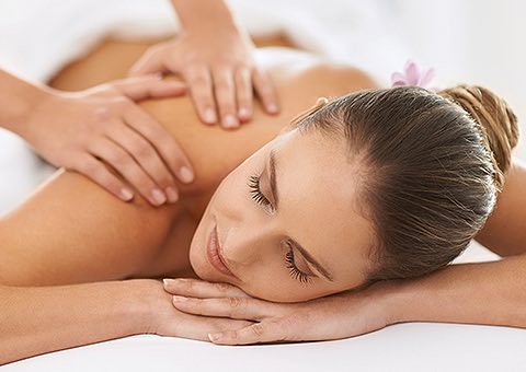 woman with her hair in a bun laying down and getting massaged