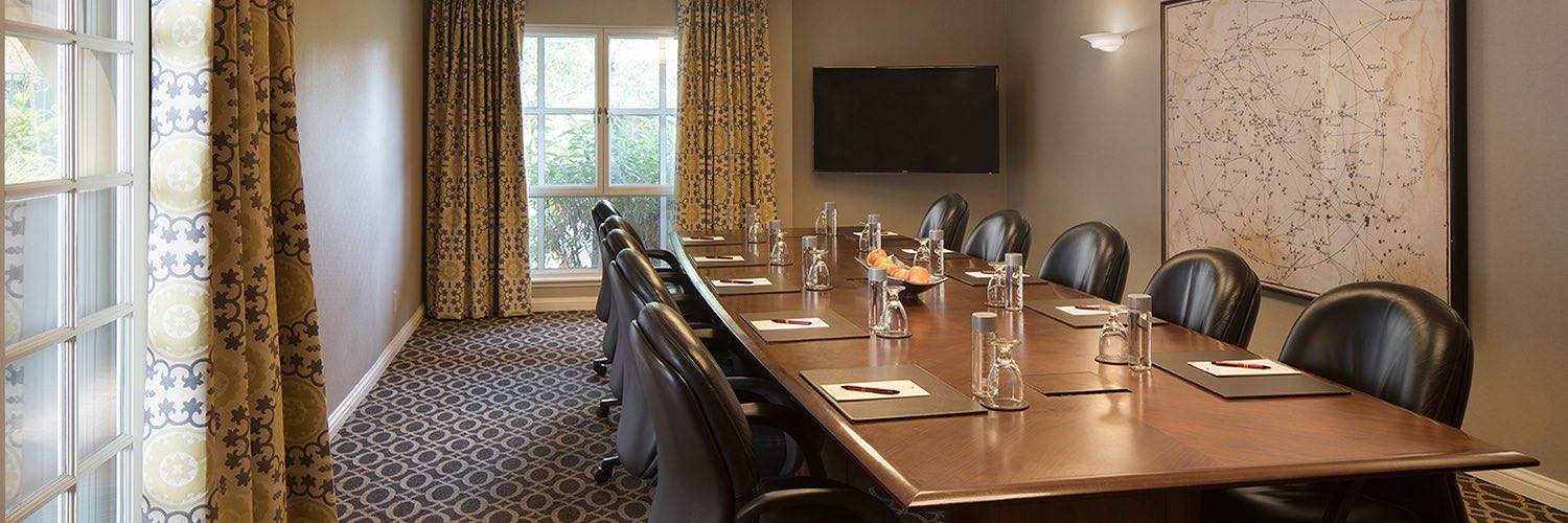 a meeting room with a conference table, chairs, a map on the wall and water bottles and folders on the table