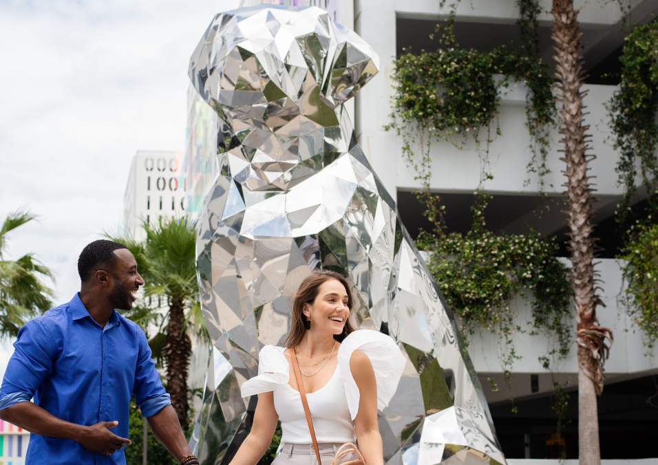 couple holding hands in front of disco the dog sculpture