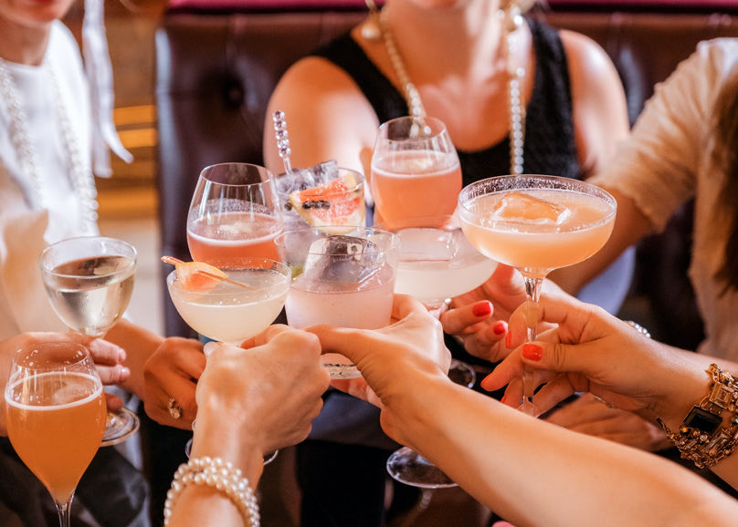 group of women clinking various cocktails together