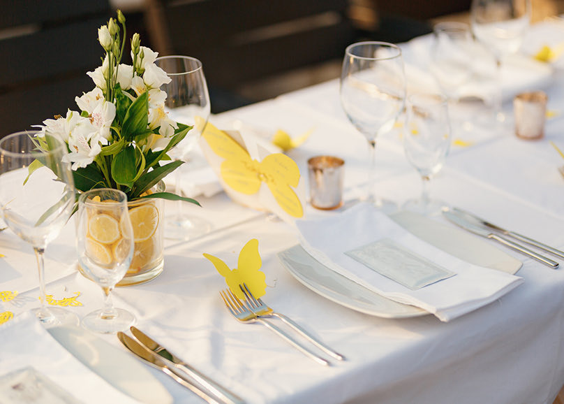 place setting with flowers in a vase with lemons as a centerpiece