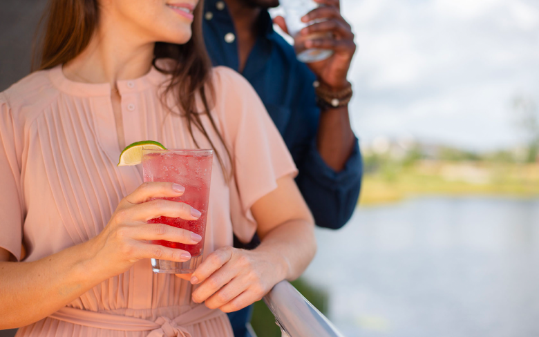 man and woman with a drink next to a lake