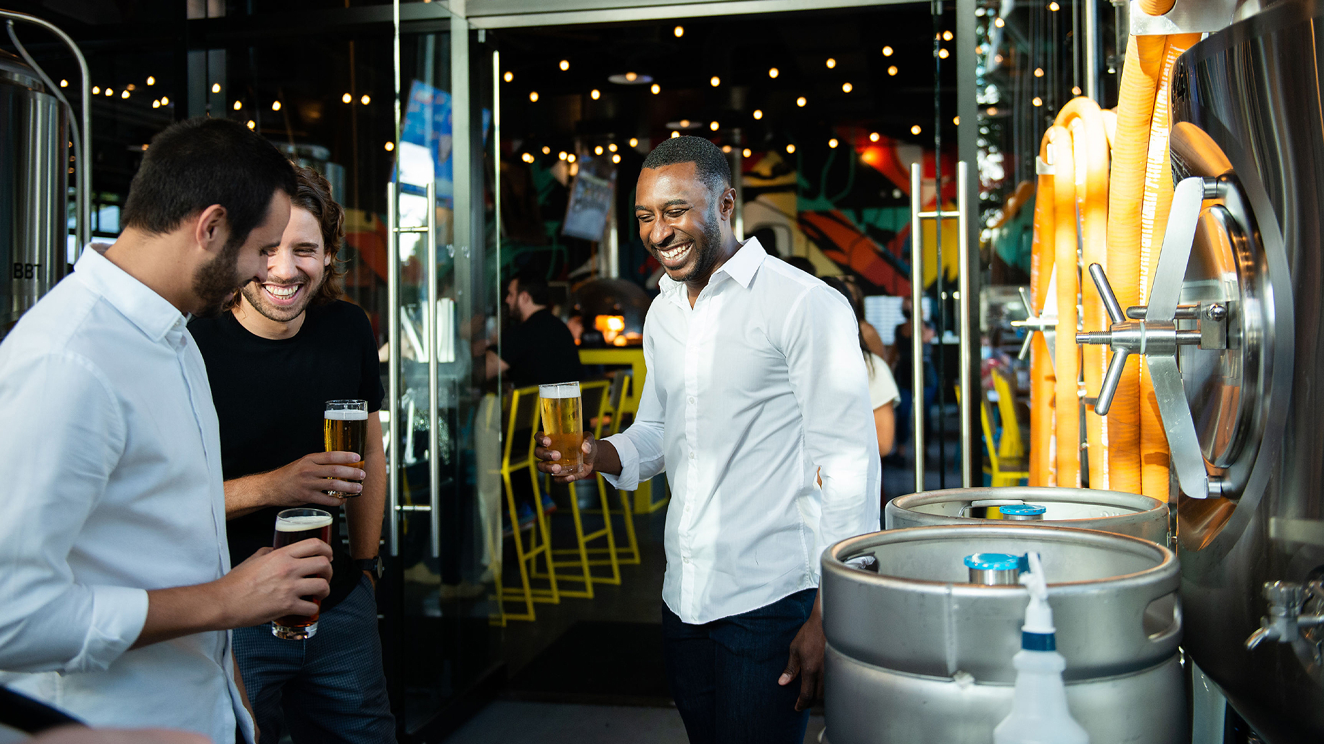 three guys laughing over beers