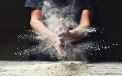 two hands together sprinkling out flour