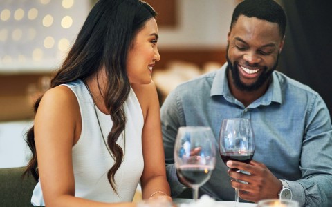man and woman smiling over wine