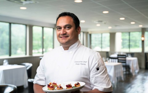 chef smiling holding plate of food