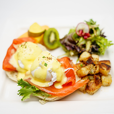 eggs benedict next to side of potatoes