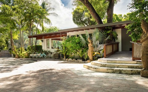 Exterior of villa with lush trees and palms on a sunny day