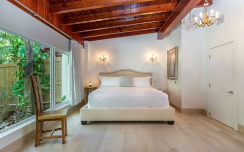 bedroom with white linens and wooden accent ceiling