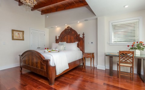 hotel bedroom with wooden bedframe and cherrywood floors